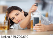 drunk woman slumped on table holding bottle of alcohol. Стоковое фото, агентство Ingram Publishing / Фотобанк Лори