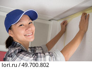 female worker using the masking tape to paint the wall. Стоковое фото, агентство Ingram Publishing / Фотобанк Лори