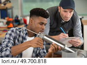 apprentice being advised how to apply caulk. Стоковое фото, агентство Ingram Publishing / Фотобанк Лори