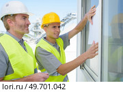 two construction workers securing window. Стоковое фото, агентство Ingram Publishing / Фотобанк Лори