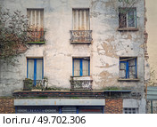 Abandoned building facade. Trees and bushes growing out of windows, rusted louvers and cracked concrete walls. Стоковое фото, агентство Ingram Publishing / Фотобанк Лори