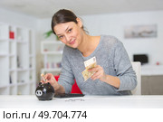 smiling woman putting notes into her piggy bank. Стоковое фото, агентство Ingram Publishing / Фотобанк Лори