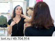 portrait of a woman trying on necklace. Стоковое фото, агентство Ingram Publishing / Фотобанк Лори