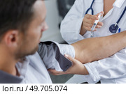doctor gives an intramuscular injection in male arm. Стоковое фото, агентство Ingram Publishing / Фотобанк Лори