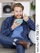 unemployed man eating cereal as he watches television. Стоковое фото, агентство Ingram Publishing / Фотобанк Лори
