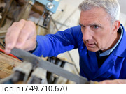 senior worker operates metalworking machine. Стоковое фото, агентство Ingram Publishing / Фотобанк Лори