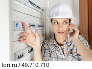 a woman builder on the phone measuring electrical current. Стоковое фото, агентство Ingram Publishing / Фотобанк Лори