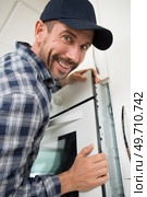 happy man installing an oven in a fitted kitchen. Стоковое фото, агентство Ingram Publishing / Фотобанк Лори