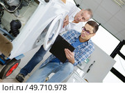 Repairman looking at washing machine on sack trucks. Стоковое фото, агентство Ingram Publishing / Фотобанк Лори