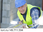 mature male builder measuring a concrete wall. Стоковое фото, агентство Ingram Publishing / Фотобанк Лори
