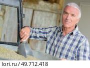 portrait of a farmer scooping dry feed. Стоковое фото, агентство Ingram Publishing / Фотобанк Лори