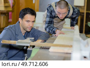 Men lining up plank of wood. Стоковое фото, агентство Ingram Publishing / Фотобанк Лори