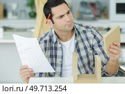worker not sure about installing kitchen cupboard. Стоковое фото, агентство Ingram Publishing / Фотобанк Лори