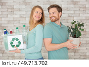 ecological couple hold a plastic container and a small tree. Стоковое фото, агентство Ingram Publishing / Фотобанк Лори