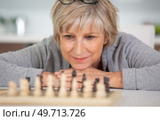 pensive senior woman sitting at table and playing chess. Стоковое фото, агентство Ingram Publishing / Фотобанк Лори