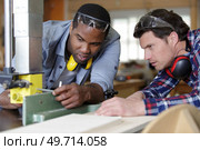 two men holding timber on woodworking machine. Стоковое фото, агентство Ingram Publishing / Фотобанк Лори
