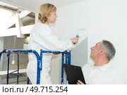 painter with female learning to use a roller. Стоковое фото, агентство Ingram Publishing / Фотобанк Лори