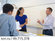 smiling teacher standing near board with students. Стоковое фото, агентство Ingram Publishing / Фотобанк Лори