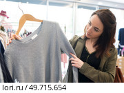 woman in clothes shop holding sweater on hanger. Стоковое фото, агентство Ingram Publishing / Фотобанк Лори