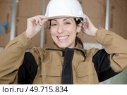 smiling female wroker adjusting her hardhat. Стоковое фото, агентство Ingram Publishing / Фотобанк Лори
