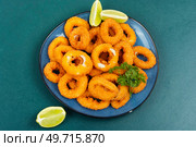 Baked breaded calamari rings served with lime. Rings of squid, unhealthy food. Стоковое фото, агентство Ingram Publishing / Фотобанк Лори