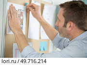 businessman pinning sticky paper memo note on cork board. Стоковое фото, агентство Ingram Publishing / Фотобанк Лори