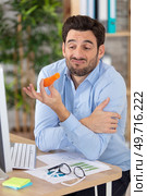 office worker disgusted face holding a carrot. Стоковое фото, агентство Ingram Publishing / Фотобанк Лори