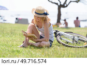 woman reading in the park bicycle layed beside her. Стоковое фото, агентство Ingram Publishing / Фотобанк Лори