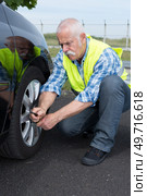 retired man has to change punctured wheel. Стоковое фото, агентство Ingram Publishing / Фотобанк Лори