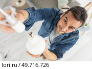 asian man changing light bulb in coffee shop. Стоковое фото, агентство Ingram Publishing / Фотобанк Лори