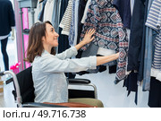 invalid girl on wheelchair choosing clothes in a store. Стоковое фото, агентство Ingram Publishing / Фотобанк Лори