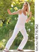 young woman praticing tai chi chuan outdoors in the sunshine. Стоковое фото, агентство Ingram Publishing / Фотобанк Лори