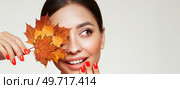 Portrait of beautiful young woman with autumn leafs. Healthy clean fresh skin natural make up beauty eyes and red nails. Стоковое фото, агентство Ingram Publishing / Фотобанк Лори