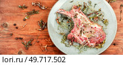 Raw fresh pork steak Tomahawk marinated in spicy herbs on wooden background. Copy space.. Raw pork steak Tomahawk, space for text. Стоковое фото, агентство Ingram Publishing / Фотобанк Лори