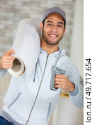 workman holding a roll of materials and a staple-gun. Стоковое фото, агентство Ingram Publishing / Фотобанк Лори