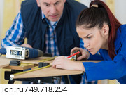 Tutor watching apprentice measuring wood. Стоковое фото, агентство Ingram Publishing / Фотобанк Лори