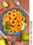 Baked breaded calamari rings on rustic wooden table.. Deep fried squid rings. Стоковое фото, агентство Ingram Publishing / Фотобанк Лори