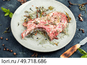 Raw pork steak Tomahawk marinated in spicy herbs on stone background. Raw barbecue Tomahawk steak. Стоковое фото, агентство Ingram Publishing / Фотобанк Лори