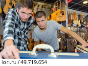 Two young men in musical instrument shop. Стоковое фото, агентство Ingram Publishing / Фотобанк Лори