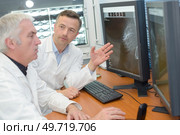doctors looking to x-ray scan on monitor at clinic. Стоковое фото, агентство Ingram Publishing / Фотобанк Лори