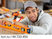 happy craftsman measuring floor level. Стоковое фото, агентство Ingram Publishing / Фотобанк Лори