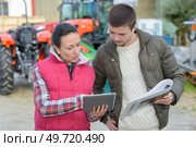 saleswoman showing tractors brand capabilities to farmer client. Стоковое фото, агентство Ingram Publishing / Фотобанк Лори