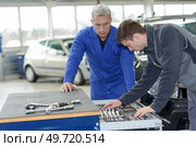teacher and student choosing appropriate tools in mechanic school. Стоковое фото, агентство Ingram Publishing / Фотобанк Лори