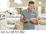 Man laughing while reading a book. Стоковое фото, агентство Ingram Publishing / Фотобанк Лори