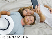 couple taking selfie on hotel bed. Стоковое фото, агентство Ingram Publishing / Фотобанк Лори
