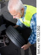 aged man changing leaking tire on the verge. Стоковое фото, агентство Ingram Publishing / Фотобанк Лори