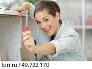 woman showing screwdriver she is using to assemble cupboard. Стоковое фото, агентство Ingram Publishing / Фотобанк Лори