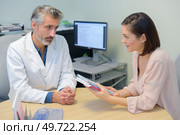 Doctor with female patient holding booklets. Стоковое фото, агентство Ingram Publishing / Фотобанк Лори