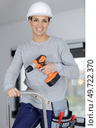 female contractor on stepladder holding cordless power-tool. Стоковое фото, агентство Ingram Publishing / Фотобанк Лори