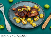 Roasted ostrich steak and mini kiwi on a plate. Grilled ostrich steak with kiwi berries. Стоковое фото, агентство Ingram Publishing / Фотобанк Лори